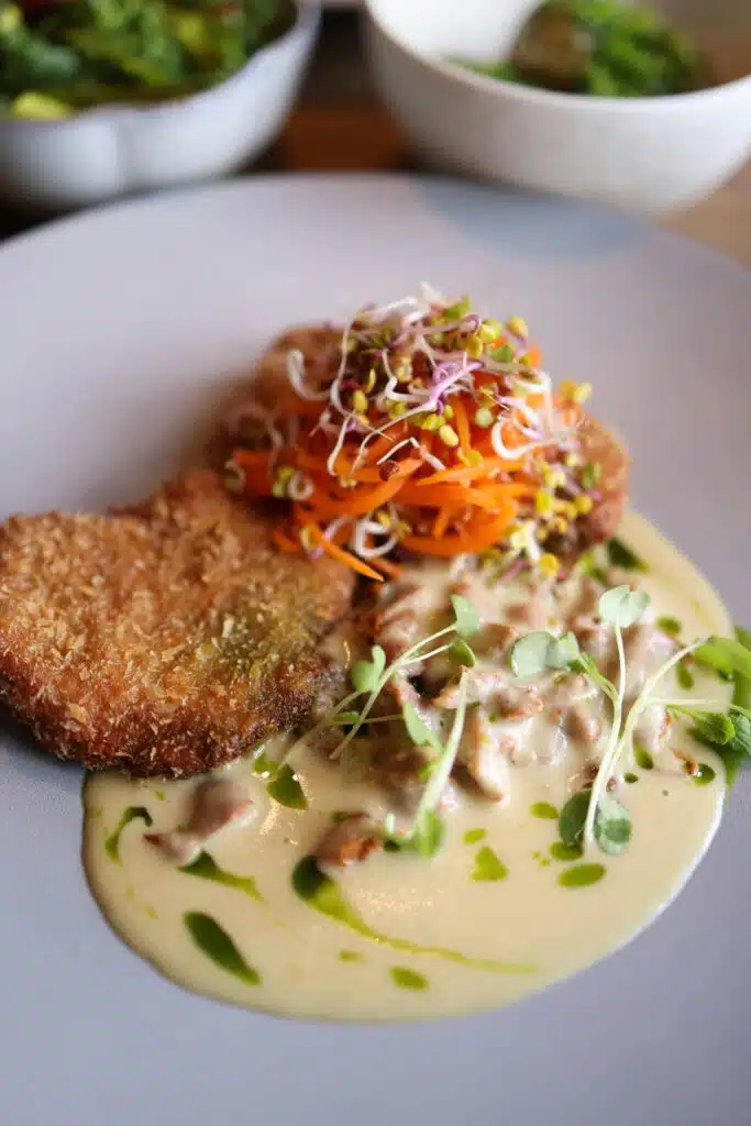 Escalope panée croustillante sur sauce crémeuse aux champignons, carottes et pousses fraîches, restaurant ARIA Paris
