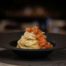 Spaghetti en nid avec gambas sautées et parmesan râpé dans un bol noir profond, restaurant ARIA Paris