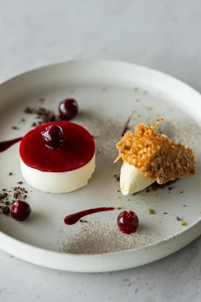 Panna cotta miroir cerise, quenelle de crème glacée et tuile caramélisée sur assiette texturée, restaurant ARIA Paris