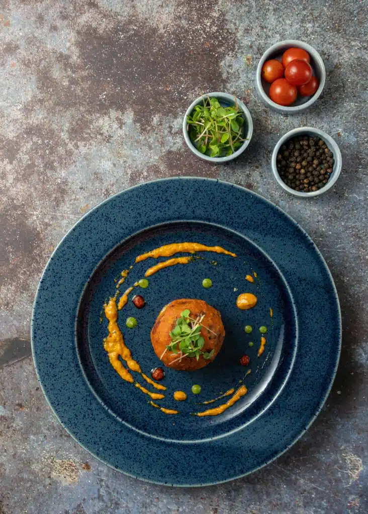 Gambas pochées sur crème de butternut, écume légère et micro-herbes dans un bol noir mat, restaurant ARIA Paris