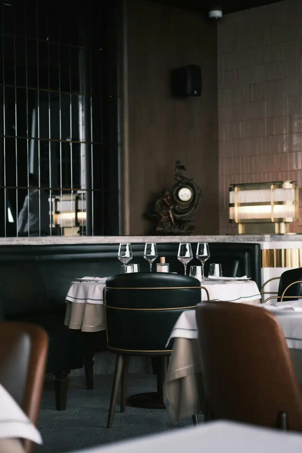 Salle du restaurant gastronomique ARIA à Paris, tables dressées et fauteuils en cuir dans une atmosphère intime et raffinée
